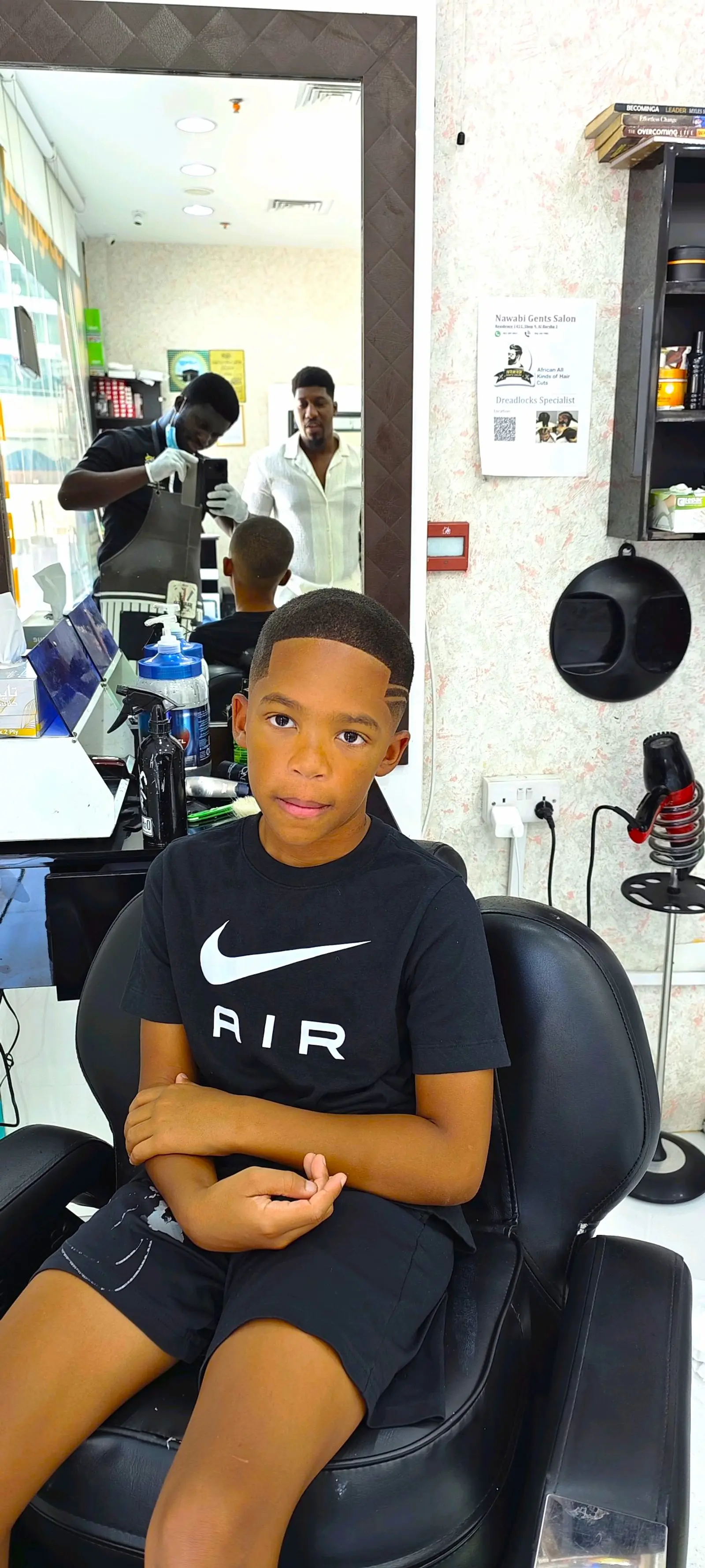 young boy with fresh haircut sitting in barber chair at Kings Afro Barbershop in JVC Dubai